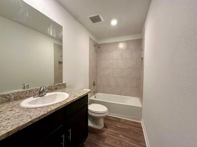 a bathroom with a granite countertop sink a toilet a mirror and shower