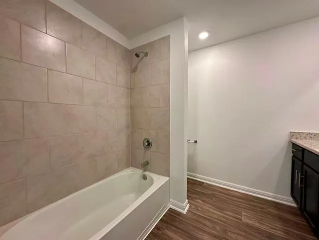 a bathroom with a tub shower and vanity