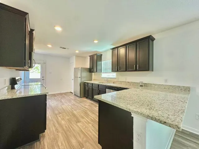 a kitchen with stainless steel appliances granite countertop a sink stove and refrigerator