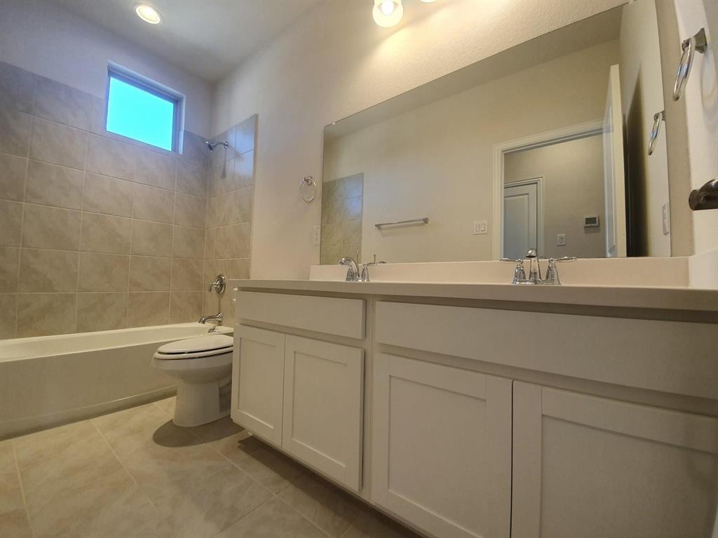 8286 Primrose Way Dallas, TX 75252 - Photo 19 of 25 a bathroom with a granite countertop toilet a sink and a mirror