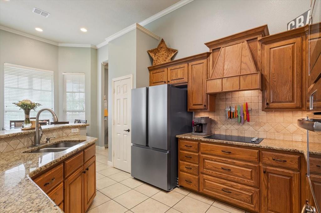 5616 Landsdown Drive Waco, TX 76708 - Photo 11 of 33 Kitchen featuring granite countertops, wood cabinetry, tile flooring, a built-in cooktop, and a stainless steel refrigerator