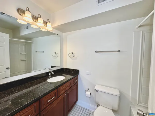 a bathroom with a granite countertop sink a toilet and a mirror