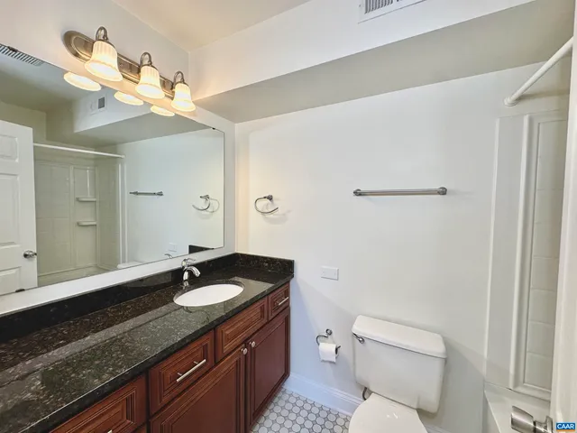 a bathroom with a granite countertop sink a toilet and a mirror