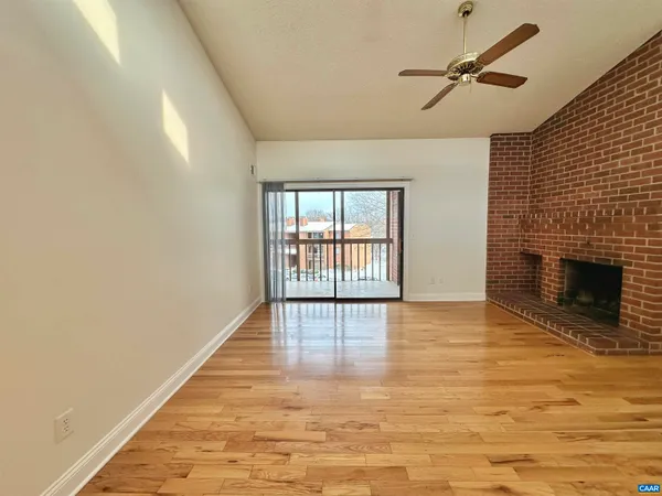 a view of empty room with wooden floor and fireplace
