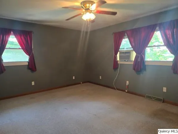 an empty room with a window and a chandelier