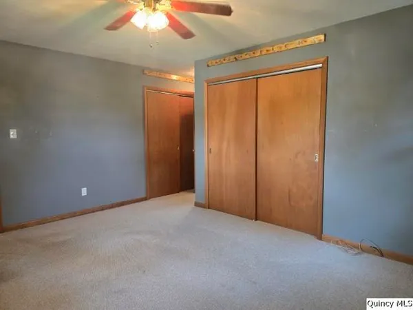 an empty room with a chandelier fan and windows