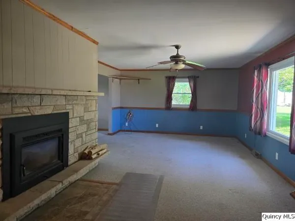 an empty room with windows and fireplace