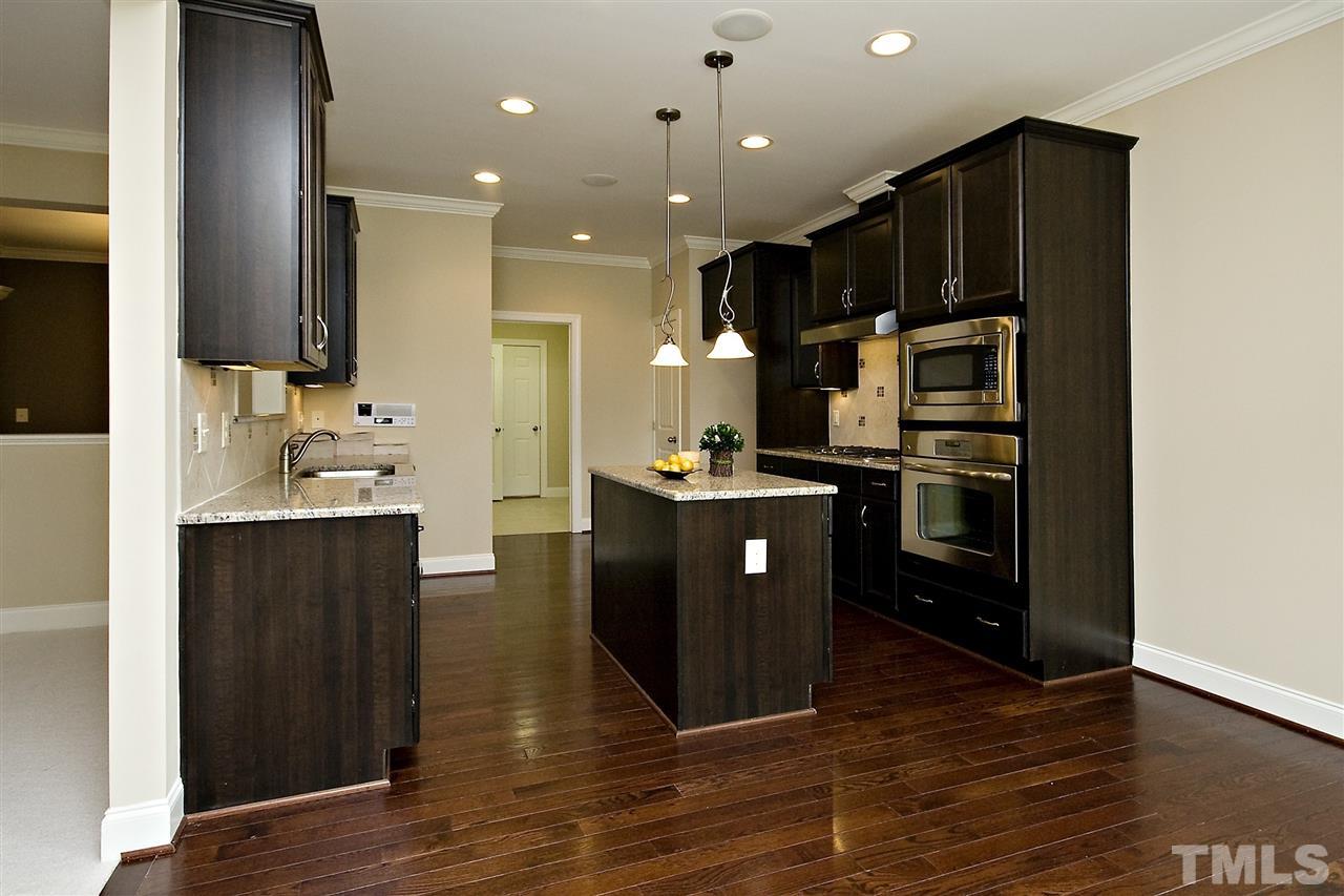 7724 Wilderness Road Raleigh, NC 27613 - Photo 3 of 7 a kitchen with stainless steel appliances kitchen island granite countertop a refrigerator a sink and wooden floor