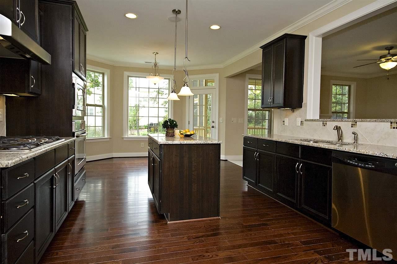 7724 Wilderness Road Raleigh, NC 27613 - Photo 4 of 7 a large kitchen with stainless steel appliances a large counter top a stove and a refrigerator