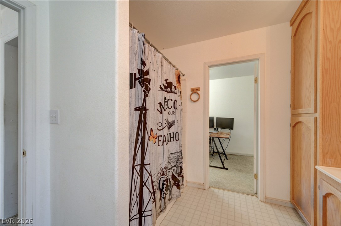 590 East Encinitas Street Searchlight, NV 89046 - Photo 33 of 39 This interior hallway features warm wooden cabinetry and durable flooring, connecting to an adjacent room.