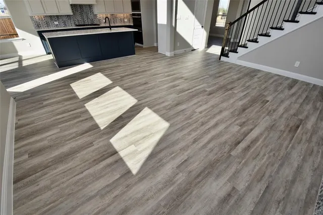 a view of kitchen and empty room with wooden floor