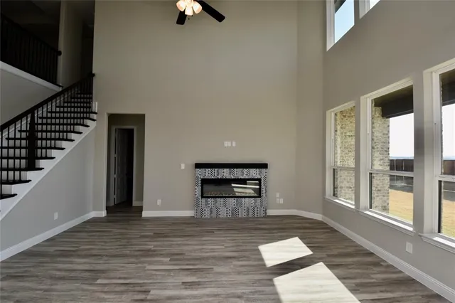 a view of an empty room with wooden floor kitchen view and a window