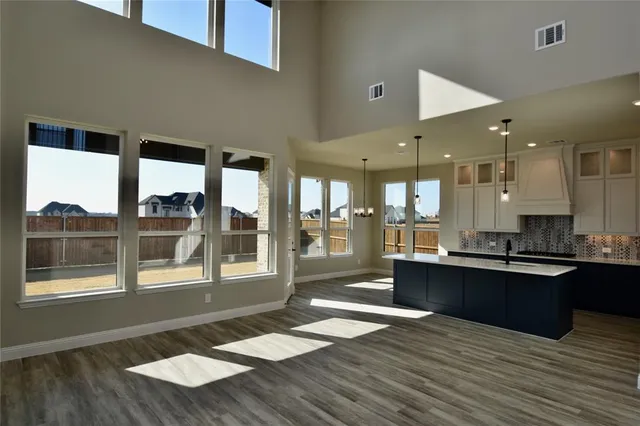 a open kitchen with granite countertop a stove top oven a sink with wooden cabinets and floor