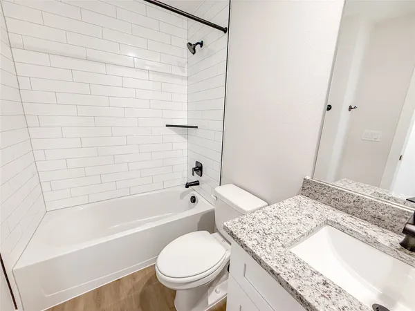 a bathroom with a granite countertop toilet a sink and bathtub