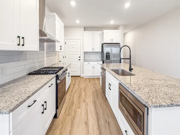 a large kitchen with stainless steel appliances granite countertop a lot of counter space sink and cabinets