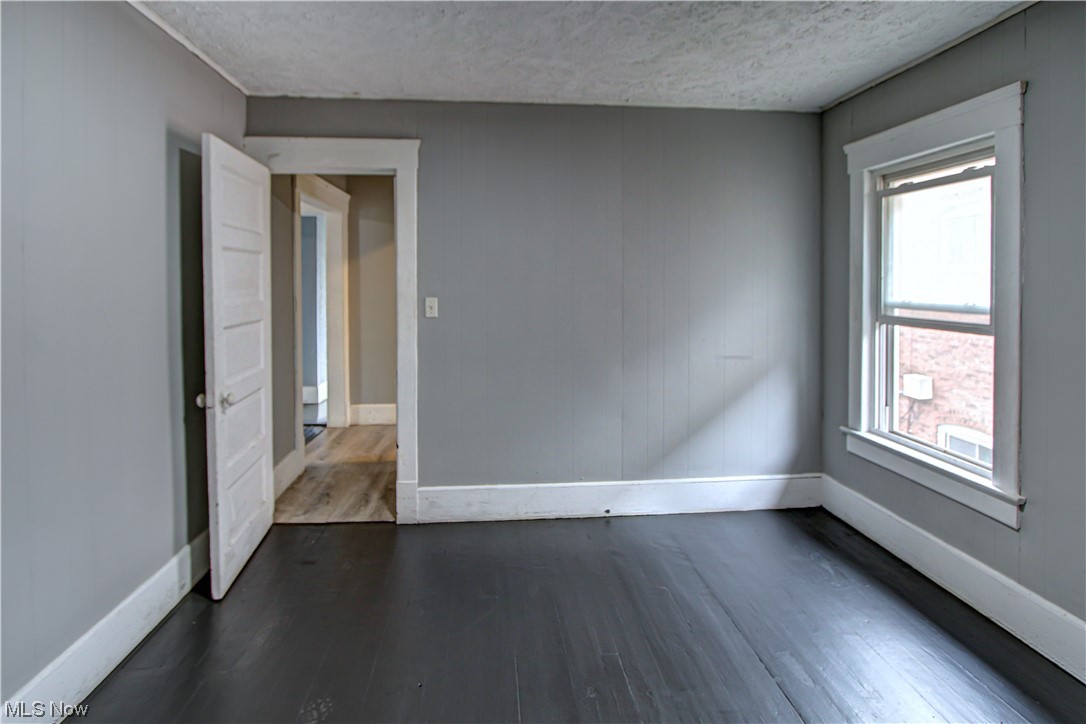3816 Riverside Avenue Cleveland, OH 44109 - Photo 13 of 35 Spare room with dark hardwood floors and a textured ceiling