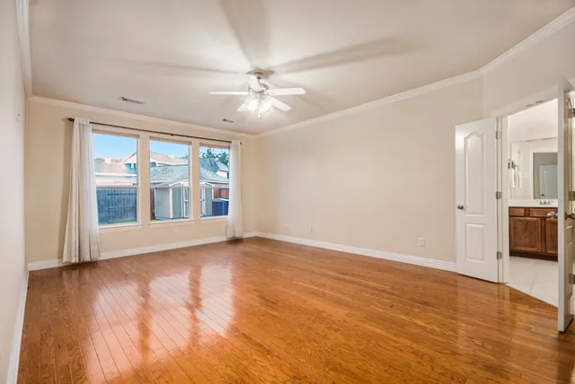 a view of an empty room with a window and wooden floor