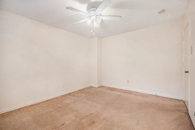 an empty room with window and a ceiling fan