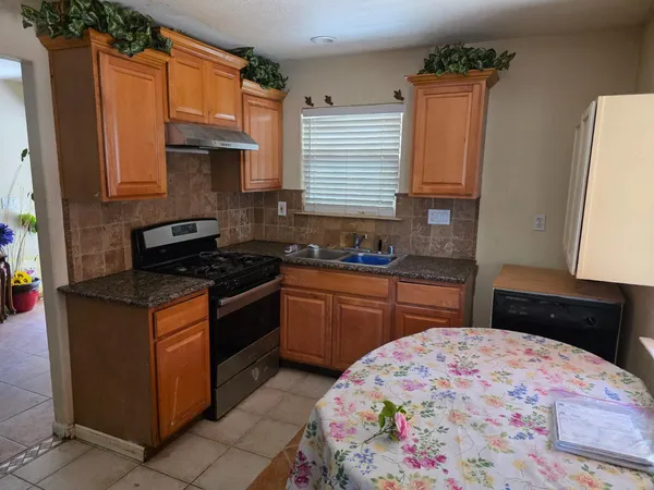 a kitchen with granite countertop a sink stove and cabinets