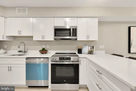 a kitchen with stainless steel appliances granite countertop a stove a sink and a microwave