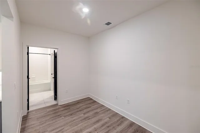 a view of an empty room with wooden floor and closet