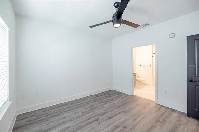 a view of empty room with wooden floor and fan