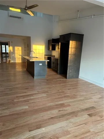 a living room with stainless steel appliances kitchen island granite countertop a sink and a microwave