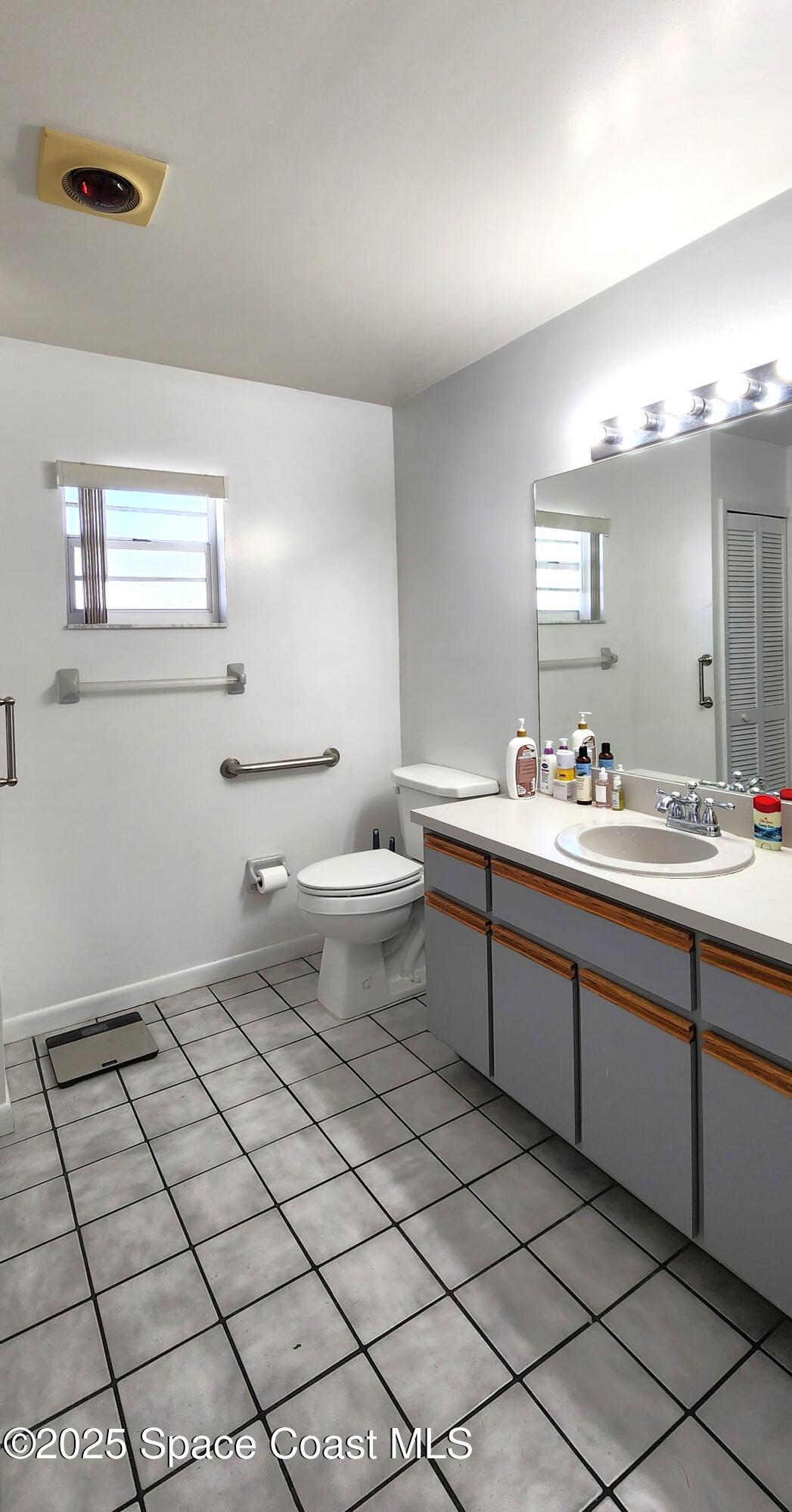 7746 Mango Grove Avenue Melbourne, FL 32904 - Photo 7 of 17 a bathroom with a double vanity sink mirror and toilet