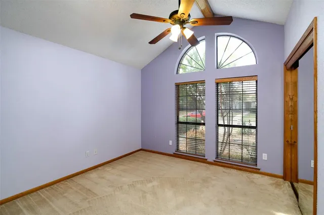 an empty room with windows and ceiling fan
