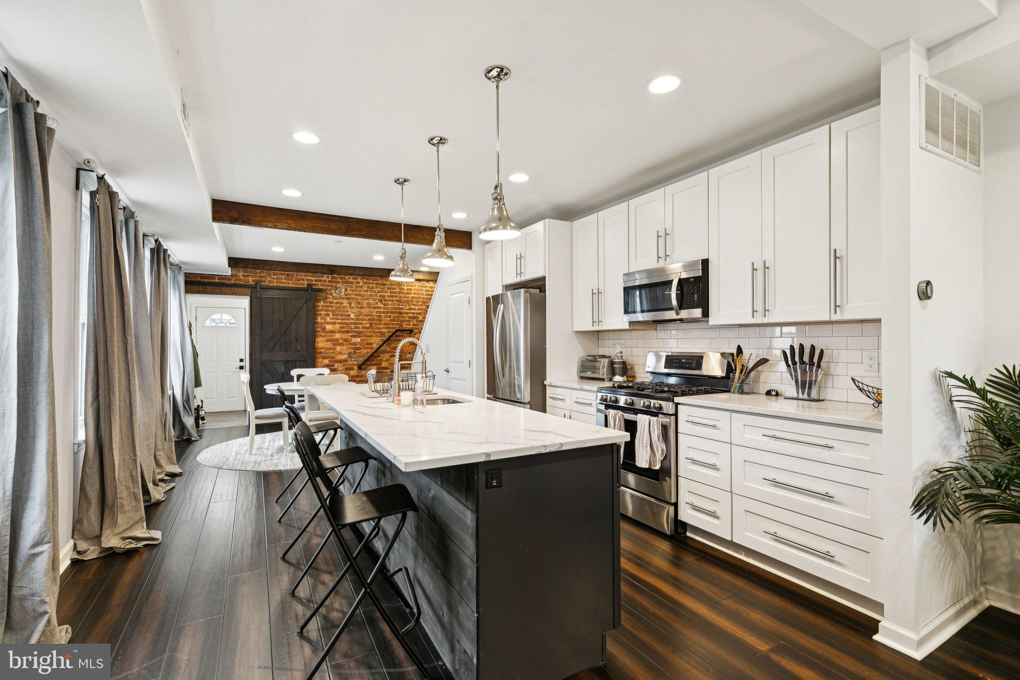359 Lemonte Street Philadelphia, PA 19128 - Photo 6 of 37 a kitchen with stainless steel appliances a stove top oven a refrigerator a sink and white cabinets with wooden floor