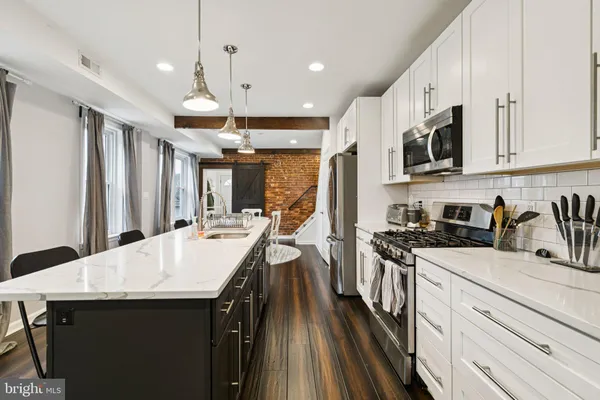 a kitchen with a sink a stove cabinets and a wooden floor