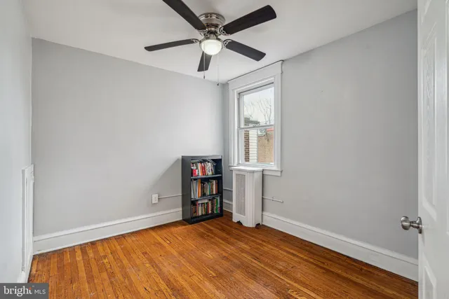 a view of empty room with wooden floor and fan