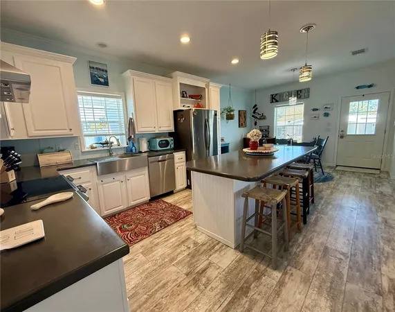 a kitchen with stainless steel appliances granite countertop a table chairs sink refrigerator and cabinets