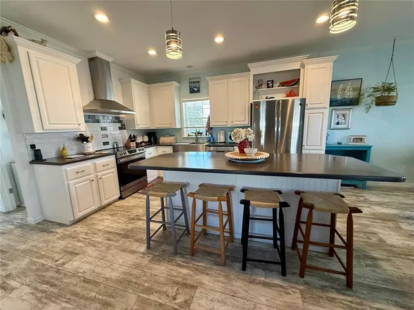a kitchen with a refrigerator a stove a sink a dining table and chairs