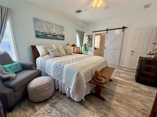 a bedroom with a bed painting on wall and a large window
