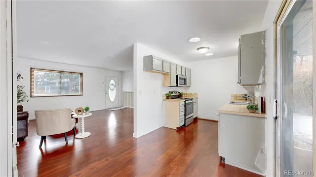 a kitchen with stainless steel appliances wooden floor and a refrigerator