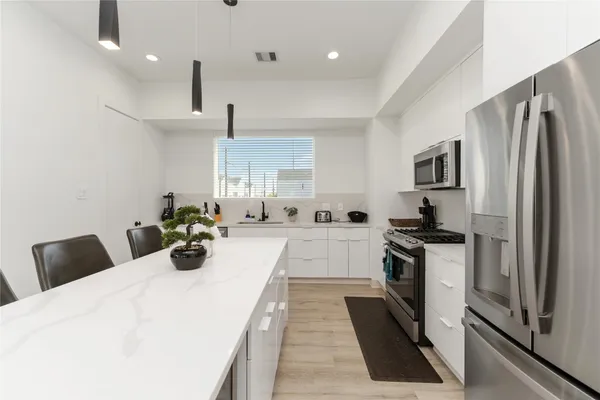 a kitchen with granite countertop a refrigerator stove and sink