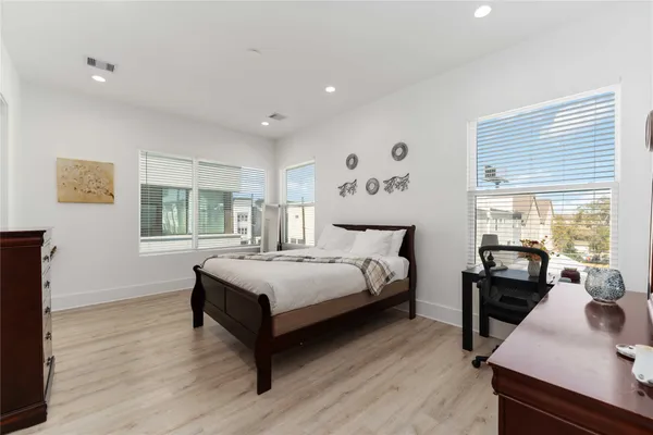 a spacious bedroom with a bed and wooden floor