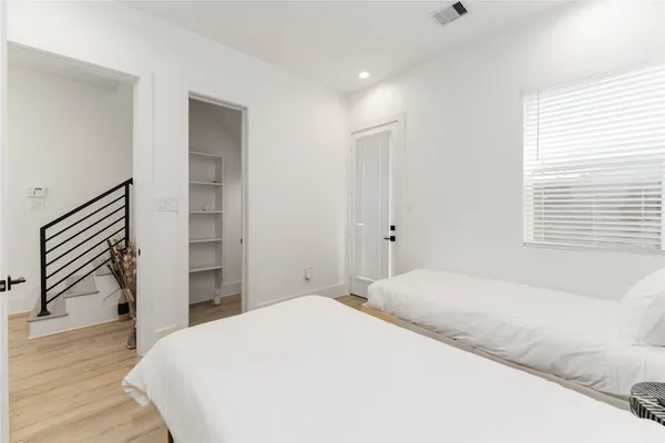 a bedroom with a bed and a dresser with wooden floor