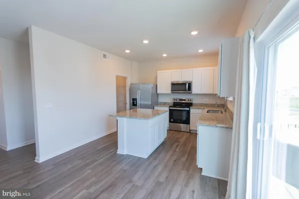 a large living room with stainless steel appliances granite countertop a stove a sink dishwasher and a flat screen tv