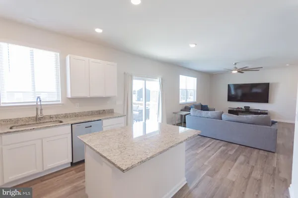a living room with a couches and kitchen view with wooden floor