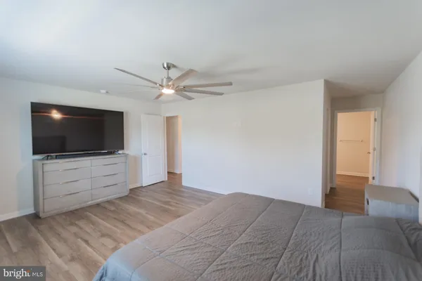 a view of empty room with wooden floor and fan