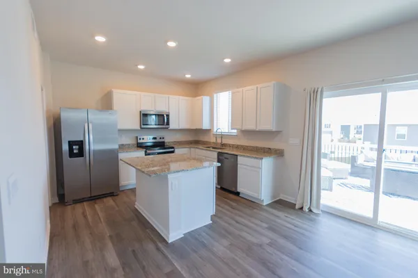 a kitchen with granite countertop a stove top oven a sink dishwasher and a refrigerator with wooden floor