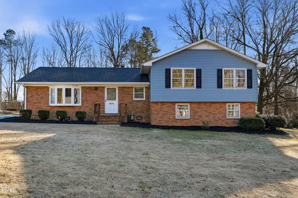a view of a yard in front of a brick house with large windows