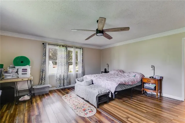 a bedroom with a bed a dresser and wooden floor