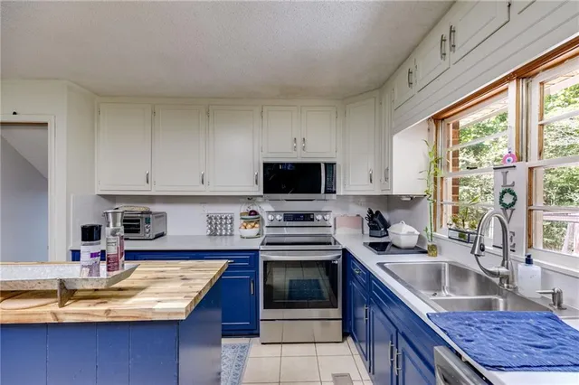 a kitchen with kitchen island granite countertop a sink appliances and cabinets