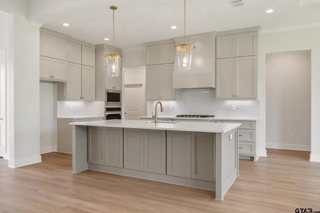 a kitchen with kitchen island granite countertop a sink cabinets and wooden floor