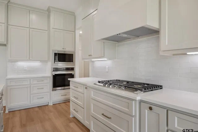 a kitchen with white cabinets and appliances