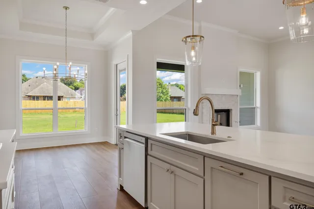 a kitchen with a sink a counter top space and living room view