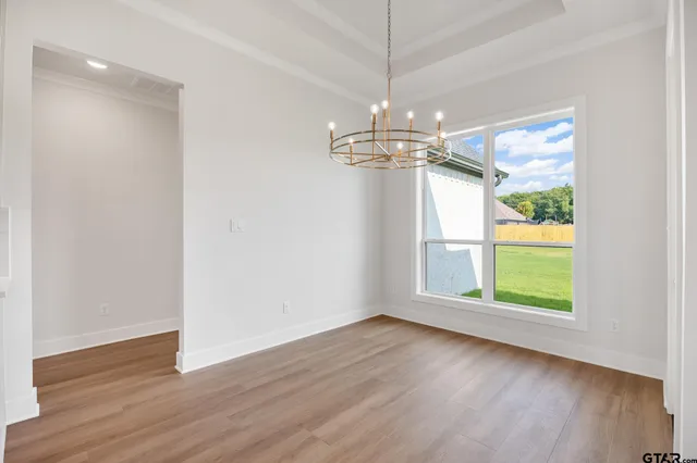 a view of a room with wooden floors chandelier and window